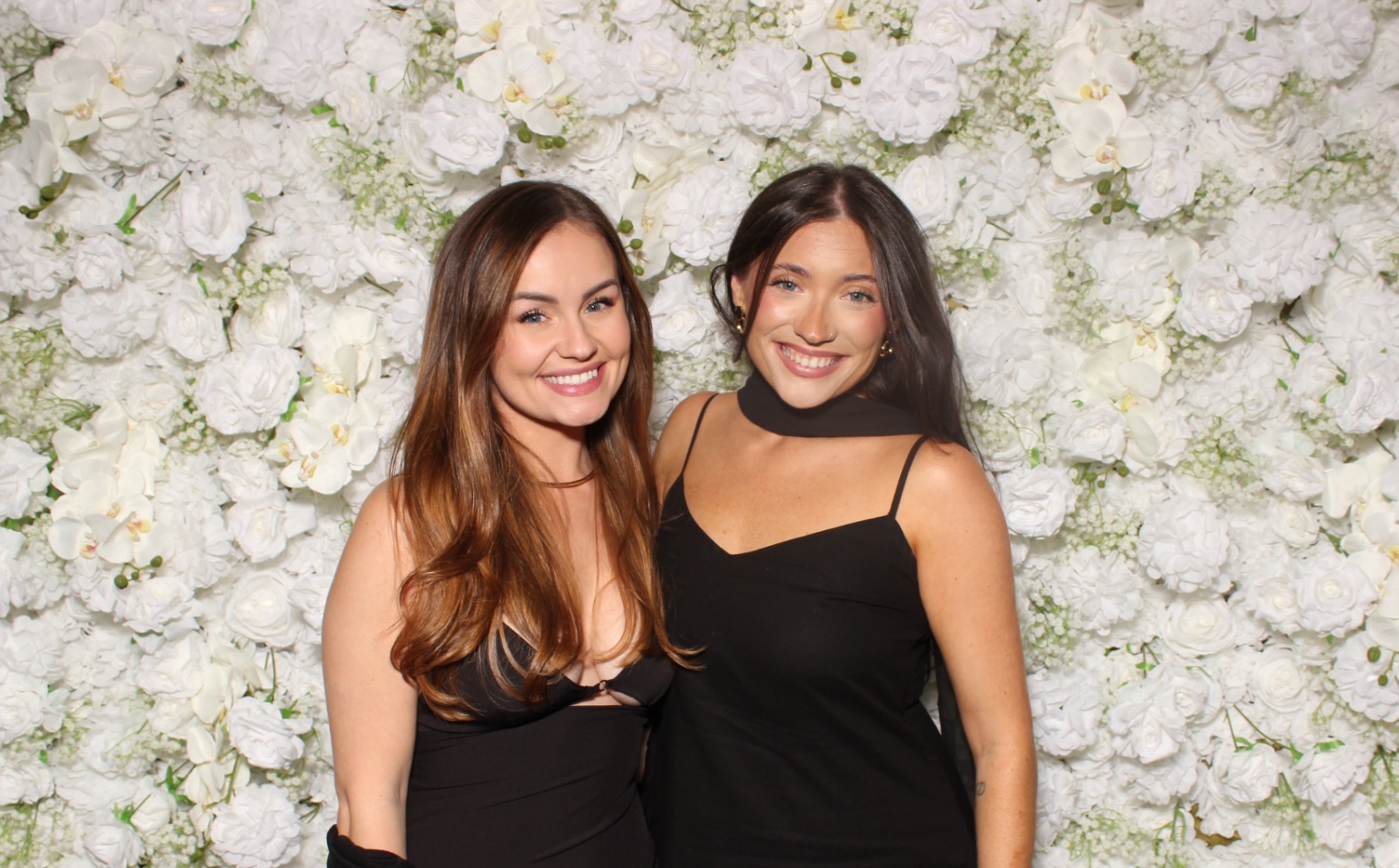 Flower wall photo booth portrait in front of a dense white floral backdrop