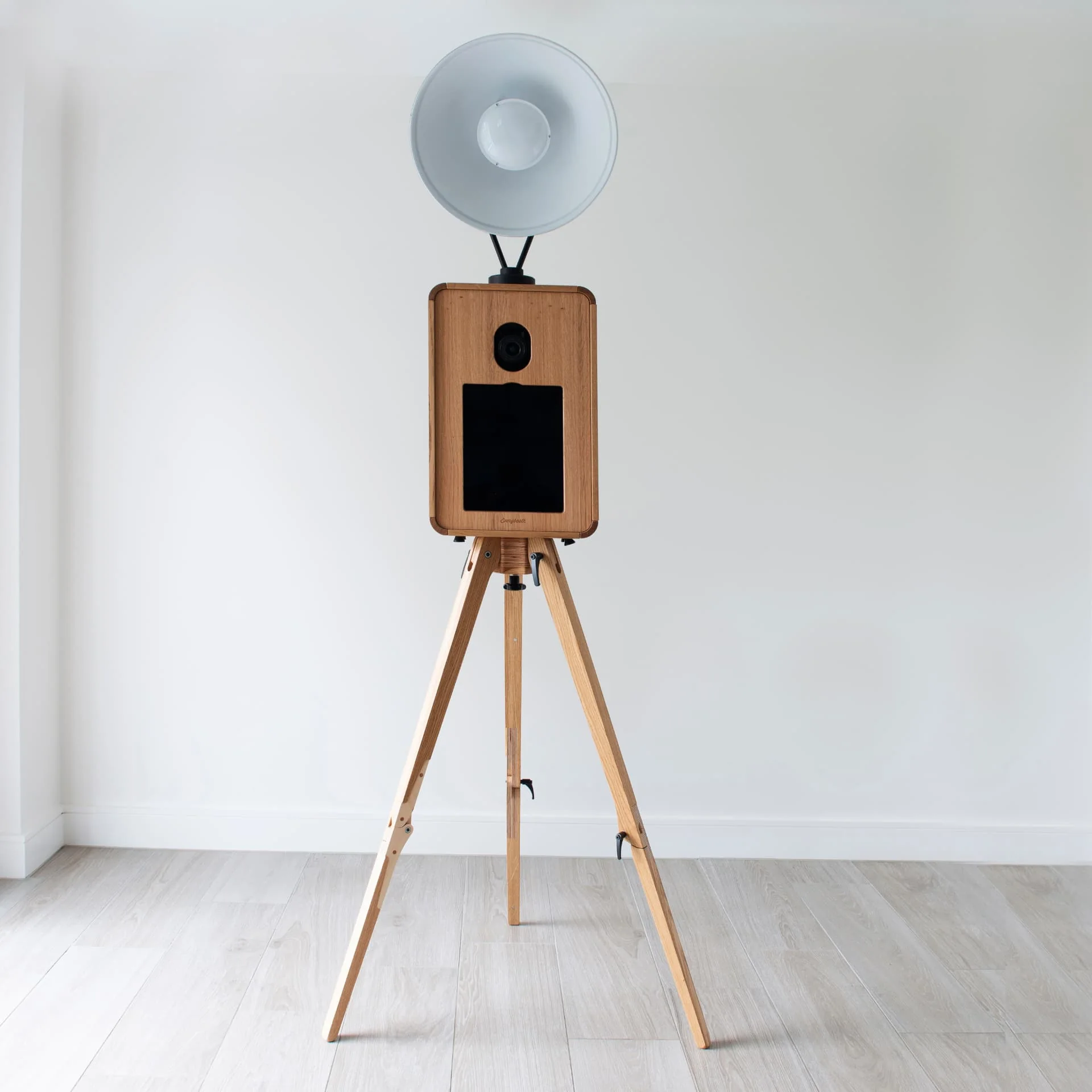 The Lux Booth oak photo booth on its wooden tripod with studio lighting