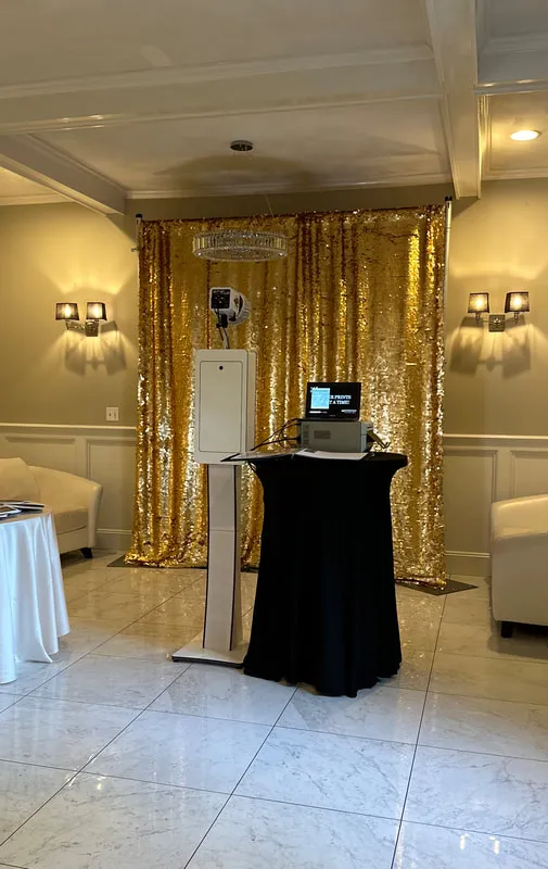 Open backdrop photo booth setup in front of a gold sequin backdrop with printer station