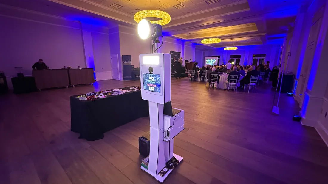 Open backdrop booth kiosk in a blue-lit ballroom during an event