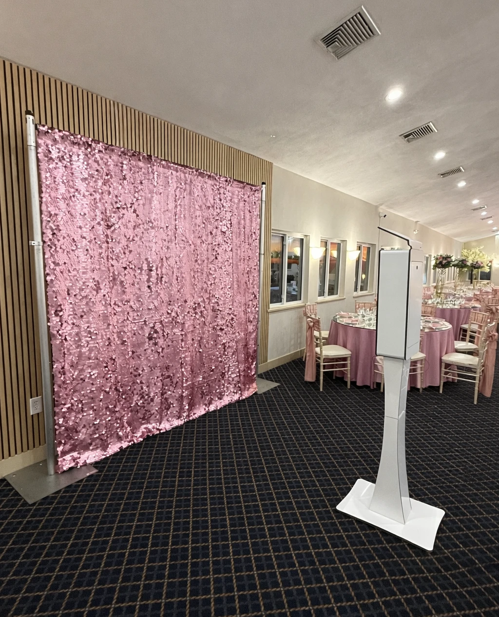 Open backdrop photo booth with rose gold sequin wall and kiosk at a pink-themed reception