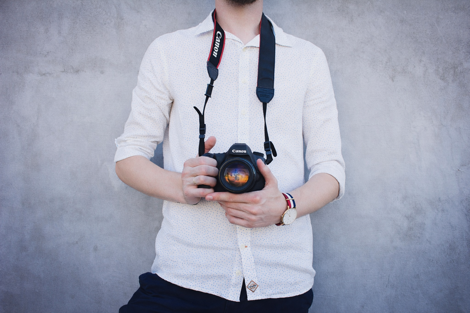 Event photographer holding a DSLR camera against a neutral backdrop
