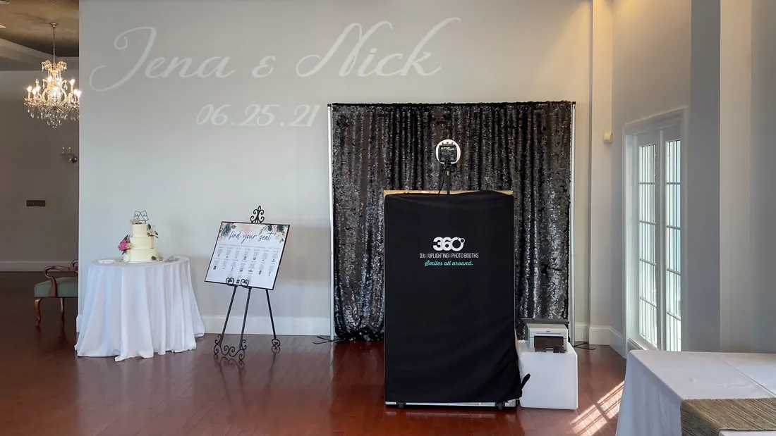 Selfie Mirror photo booth setup at a wedding with black sequin backdrop and printer
