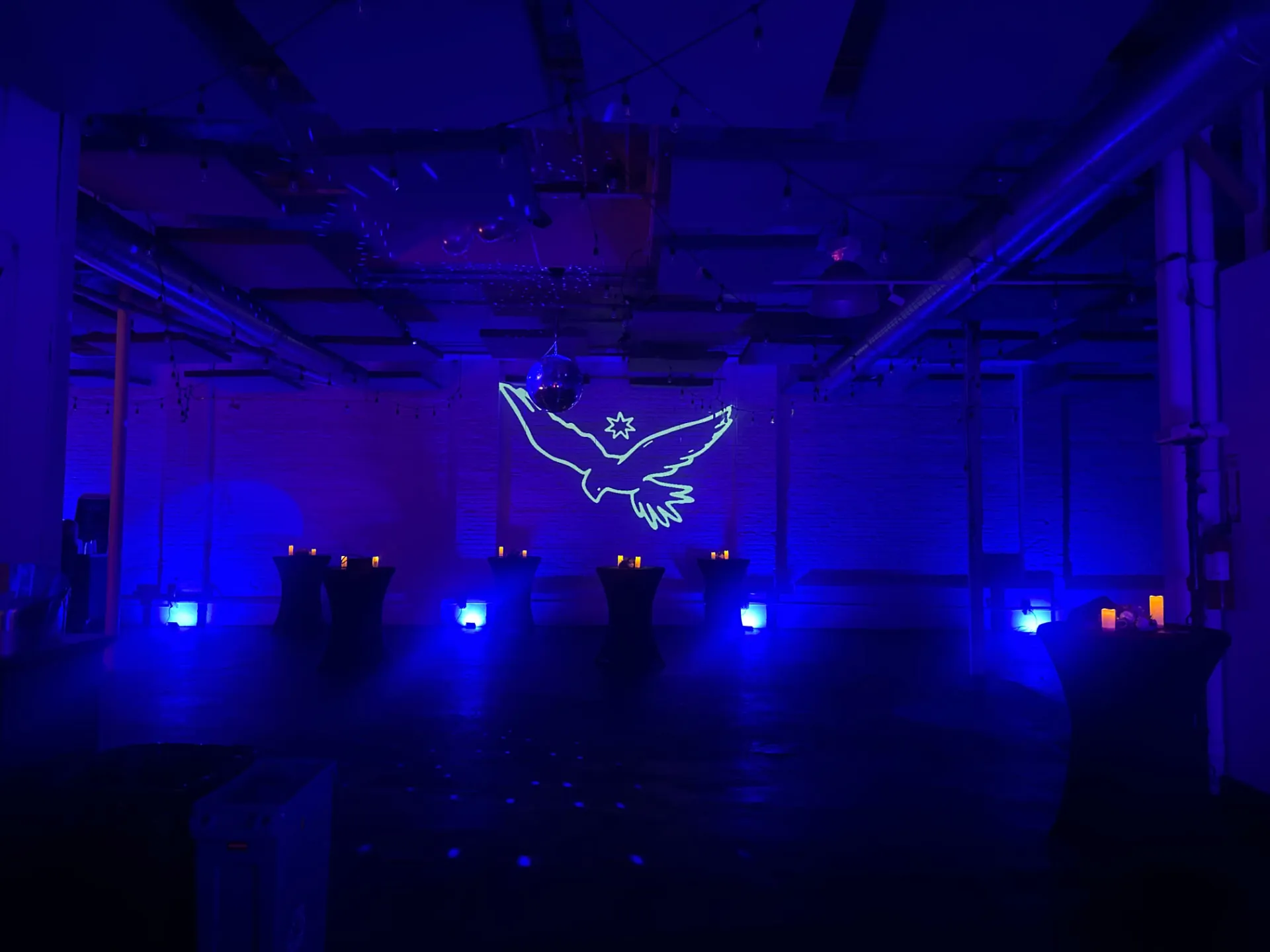 blue and purple LED uplighting across an event space with a glowing bird projection and uplit columns